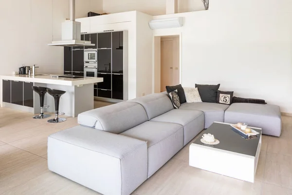 Modernes Wohnzimmer mit niedrigem Sofa und weißer und schwarzer Küche — Stockfoto