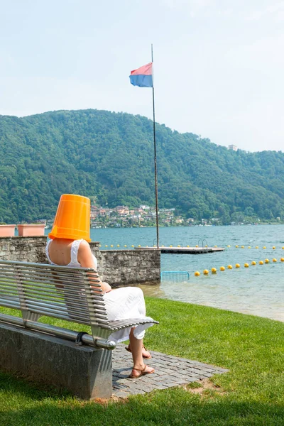 Young Woman Sitting Bench Lake Orange Bucket Her Head Secretly — Stock Photo, Image