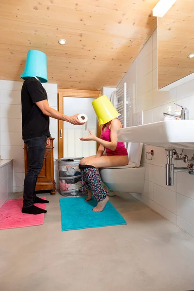 Man Bucket His Head Passes Toilet Paper His Wife Sitting — Stock Photo, Image