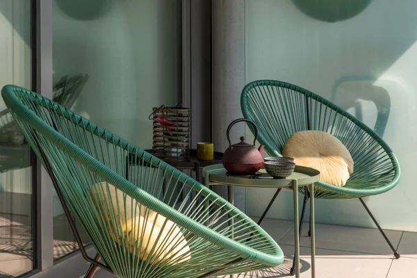 Elegant corner of a terrace of a modern house with two armchairs and a Chinese tea with two cups. Sunny summer day