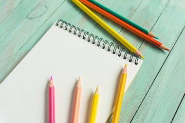 ahşap bir masa üzerinde bir eskiz defteri yanında parlak renkli kalemler