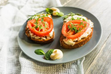 İki vejetaryen sandviç domates, tofu ve gri bir ahşap zemin üzerine nane ile