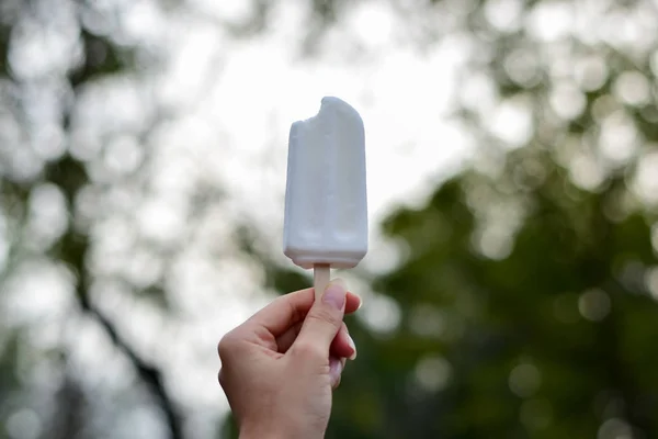 woman holding coconut ice cream in the park, delicious so should feel fresh in summer, summer light nature background.