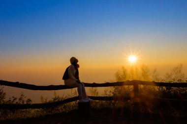 Kadın turist neşeli, siste güneşin doğuşunu izliyor.