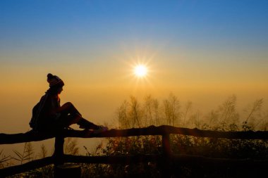Kadın turist bir histir. Rahatlar, güneşin doğuşunu seyreder.