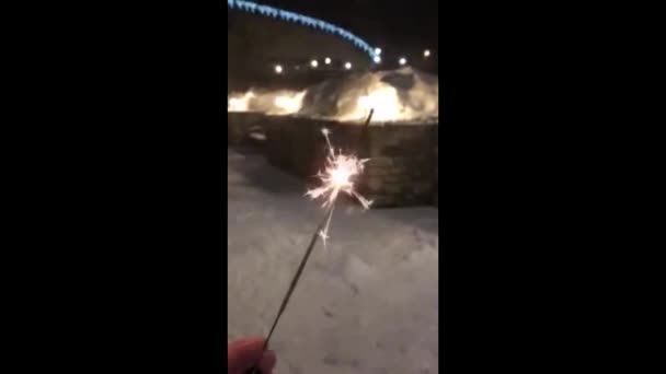 Hand met vuurwerk. Sparkler met lichte achtergrond wazig drukke stad — Stockvideo