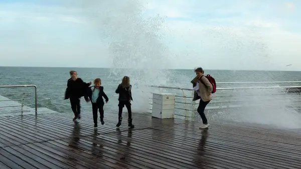 Çocuklar büyük bir dalga uzak dolgu üzerinde çalıştırın. Büyük fırtınalı deniz dalgaları seyreden.