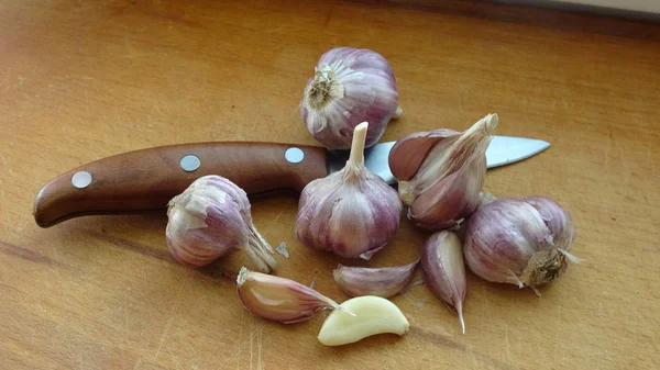 Sarımsak bir ahşap arka plan üzerinde yatıyor. Rustik ahşap arka plan üzerinde kesme tahtası üzerinde taze çiğ pembe sarımsak tam vücut portre.