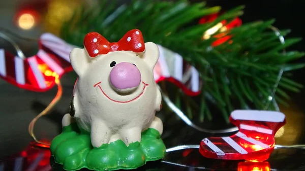 Porco de brinquedo e decoração de inverno, parabéns pelas férias. Símbolo do ano do porco no fundo das luzes de Natal — Fotografia de Stock