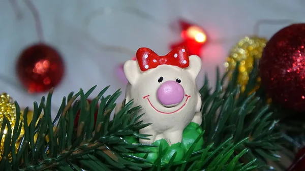 Maiale giocattolo e arredamento invernale, congratulazioni per la vacanza. Simbolo dell'anno del maiale sullo sfondo delle luci natalizie — Foto Stock