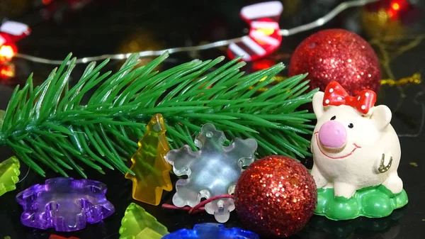 Porco de brinquedo e decoração de inverno, parabéns pelas férias. Símbolo do ano do porco no fundo das luzes de Natal — Fotografia de Stock