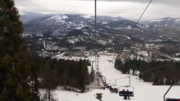 Teleférico en las montañas para esquiadores en la estación de esquí. Telesilla. La gente sube al ascensor en la estación de esquí. Esquiadores y snowboarders bajan por la pista . — Vídeos de Stock