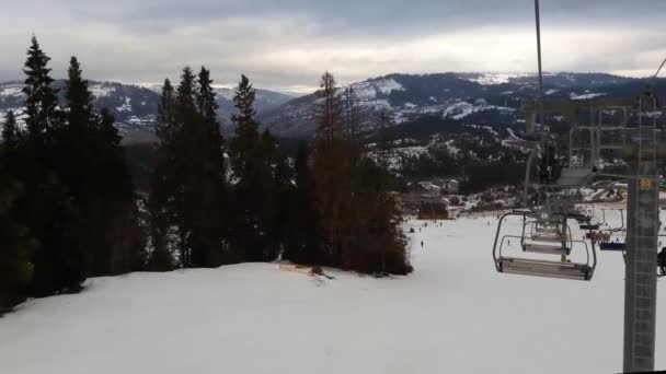 Συρματόσχοινα στα βουνά για σκιέρ στο χιονοδρομικό κέντρο. Chairlift. Άνθρωποι ανεβαίνουν τα lift στο χιονοδρομικό θέρετρο. Σκιέρ και snowboarders πηγαίνετε προς τα κάτω την πλαγιά. — Αρχείο Βίντεο