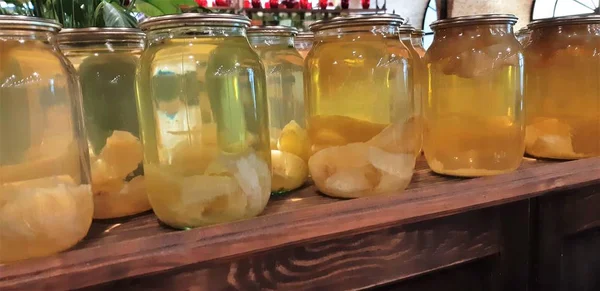 Compote de baies et pommes dans des bocaux. Plusieurs canettes colorées de compote sur une étagère en bois. Concentration sélective. Profondeur de champ faible . — Photo