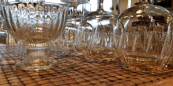 pile of empty transparent glasses on shelf. Close up of transparent clean glasses on a shelf, nested upside down stacked pile. Selective focus. Shallow depth of field.