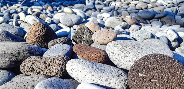 Zee pebbles close-up. Achtergrond van beach pebbles van verschillende vorm en grootte. Kiezels op de kusten van de Canarische eilanden, Tenerife — Stockfoto