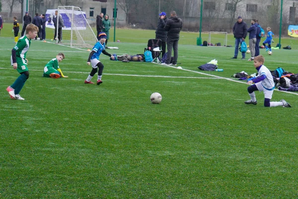Ταχύτητα παίκτης ποδοσφαίρου αγόρι τρέχει να πυροβολήσει την μπάλα στο στόχο για την πράσινη χλόη. Νεαρούς ποδοσφαιριστές που τρέχει μετά την μπάλα. — Φωτογραφία Αρχείου