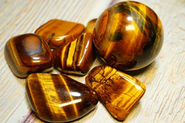 Belirli bir tür doğal mineral değerli taşlar kümesi. Ahşap bir masa üzerinde Tiger Eye Yarı değerli Değerli Gemstone Birthstone. Çeşitli cilalı değerli taşlar koleksiyonu