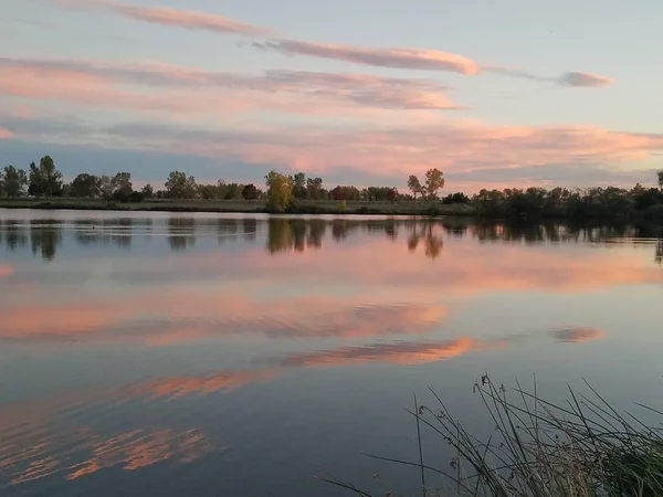 Günbatımı bir gölde yansıyan bulutlar ile