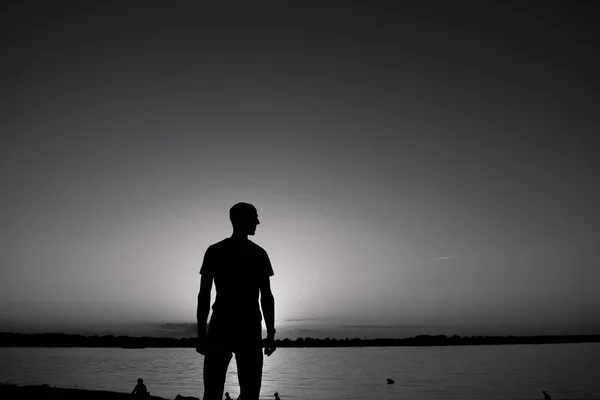 El joven está de pie ante la orilla del río con bálsamo y blanco amanecer o atardecer — Foto de Stock