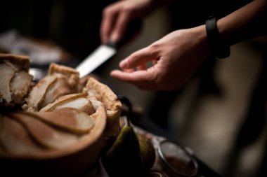 Meyveli turta kabuğu. Şefler el bir rustik mutfak masasında dilimlenmiş bıçak pasta kabuk ile kesilmiş.