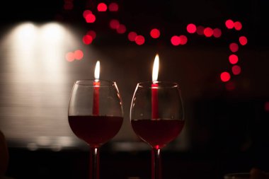 Romantik bir akşam yemeği: iki kadeh şarap ve candels çoğu karanlıkta arka yılbaşı ışıkları ile