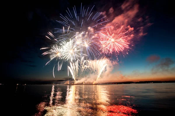 Fogos de artifício de férias acima da água com reflexão sobre o fundo do céu preto — Fotografia de Stock