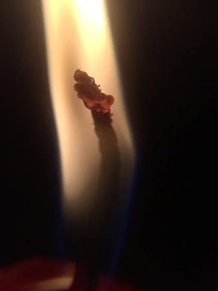 ブラーダークブラックのグラウンドで明るく燃える熱い火を持つライトキャンドル。マクロ — ストック写真