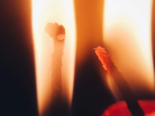 ブラーダークブラックのグラウンドで明るく燃える熱い火を持つライトキャンドル。マクロ — ストック写真