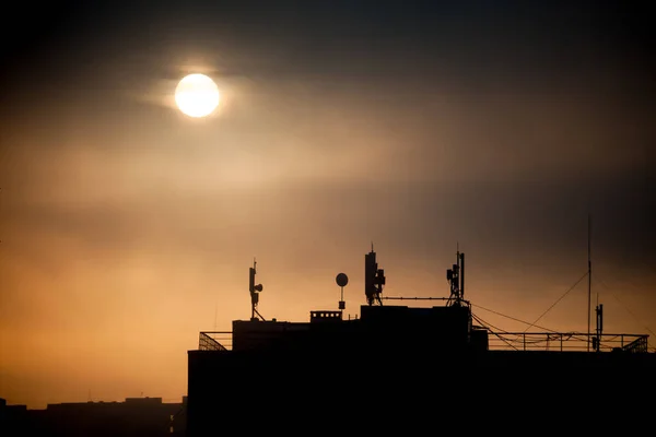 Východ slunce s siluety komunikační antény s pokrmy na střeše — Stock fotografie
