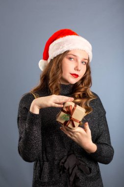 Beyaz bir kadın gri arka planda bir hediye tutuyor. izol