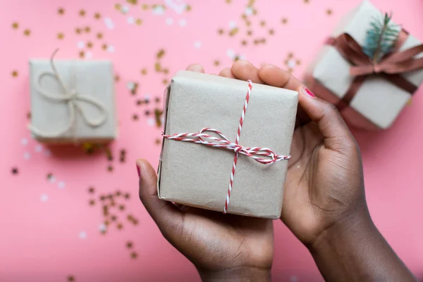 Afrikanische Frauenhände halten Geschenkbox mit Schleife auf Pastell-Nadel — Stockfoto