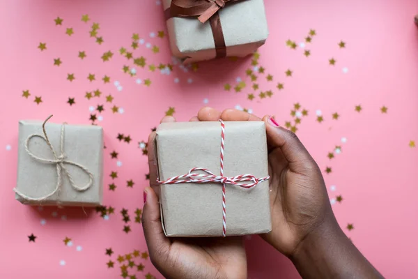 Afrikalı kadın elinde hediye kutusuyla pastel tokalı bir fiyonk tutuyor.