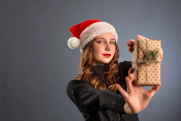Joven mujer caucásica sosteniendo un regalo sobre fondo gris. isol —  Fotos de Stock