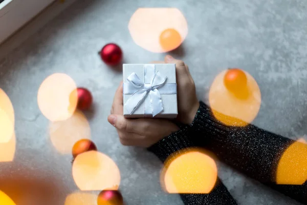 Las manos de la mujer sostienen una caja de regalo con textura artesanal con cinta —  Fotos de Stock