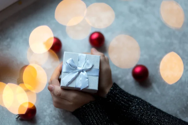 Un regalo en las manos desde arriba rodeado de juguetes de Navidad ver — Foto de Stock