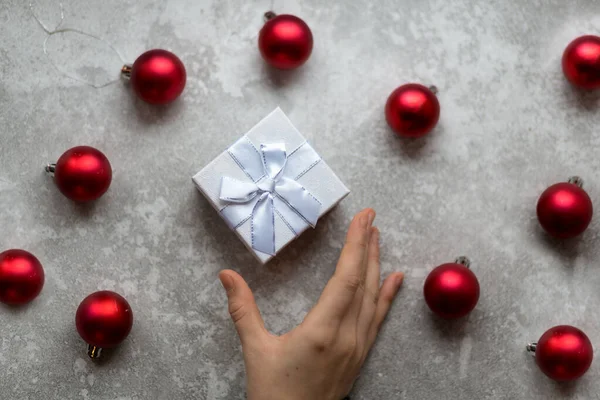 La mano de la mujer está tomando una caja de regalo con textura artesanal con lazo de cinta —  Fotos de Stock