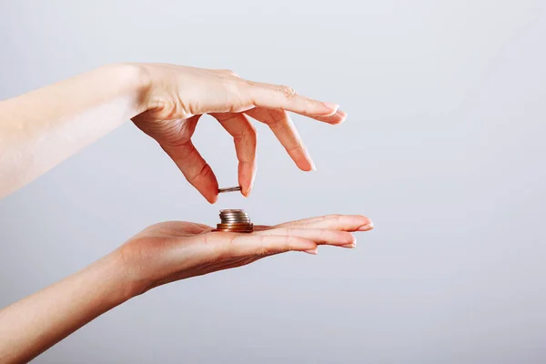 Woman\'s hand giving or taking golden coin to another hand on isolated white background, crisis concept.