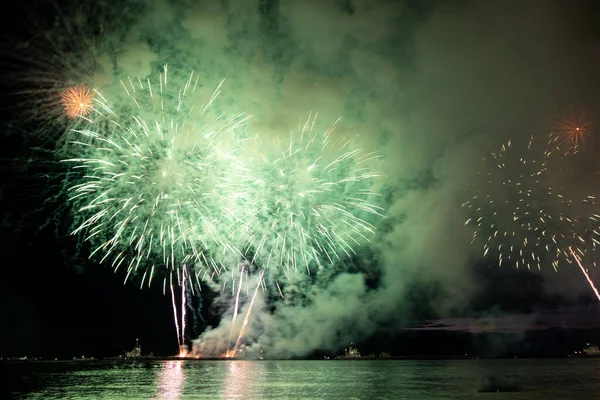 Fogos de artifício de férias acima da água com reflexão sobre o fundo do céu preto — Fotografia de Stock