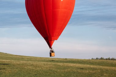 Bir grup insan, kalp şeklinde bir balonla vadi üzerinde uçuyor. İniş veya kalkış.