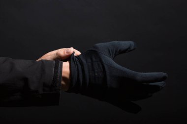 Siyah arka planda işlenen bir suçun siyah eldivenlerini teslim et. Eldivenler ele takılır. Adam eline siyah bir eldiven takıyor...