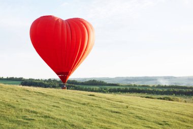 Kalp şeklinde sıcak hava balonu yeşil tepelere iniyor..