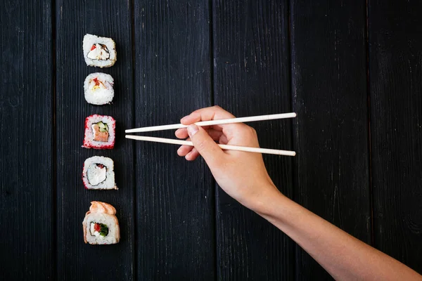 Kvinnlig Hand Tar Ätpinnar Sushi Rullar Med Kinesiska Ätpinnar Ligger — Stockfoto