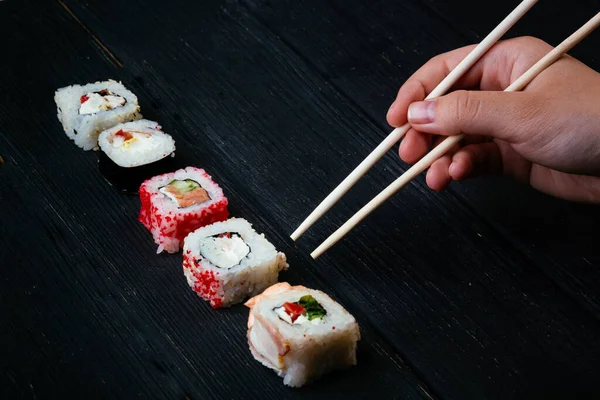 Kvinnlig Hand Tar Ätpinnar Sushi Rullar Med Kinesiska Ätpinnar Ligger — Stockfoto