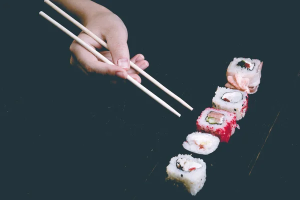 Kvinnlig Hand Tar Ätpinnar Sushi Rullar Med Kinesiska Ätpinnar Ligger — Stockfoto