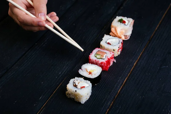 Kvinnlig Hand Tar Ätpinnar Sushi Rullar Med Kinesiska Ätpinnar Ligger — Stockfoto