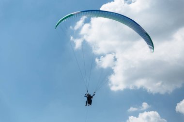 Mavi Paraglider güneşli bir günde bulutlarla gökyüzüne uçuyor..