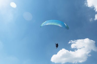 Mavi Paraglider güneşli bir günde bulutlarla gökyüzüne uçuyor..
