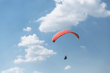 Mavi Paraglider güneşli bir günde bulutlarla gökyüzüne uçuyor..
