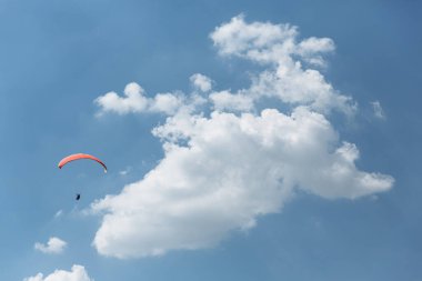 Mavi Paraglider güneşli bir günde bulutlarla gökyüzüne uçuyor.